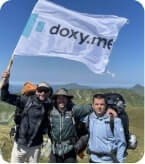 Team members waving a doxy.me flag on top of a mountain